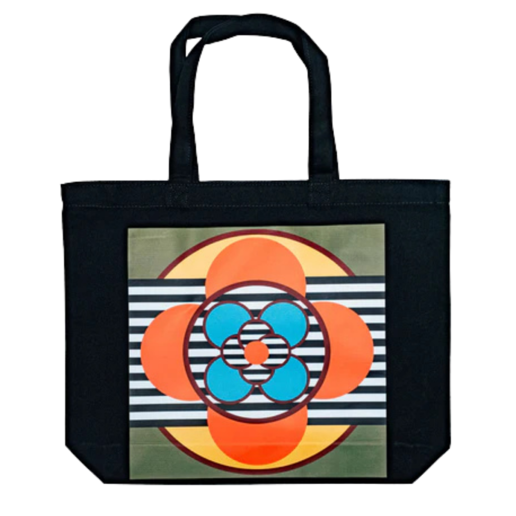 Black canvas tote bag with a bold, circular abstract design featuring orange, blue, and striped elements, created by Dahlia Elsayed.