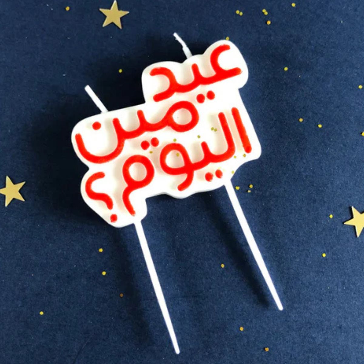 Add a spark of humor and heritage to your celebration with this Arabic birthday candle that asks, "Whose birthday is it today?" Arabic birthday candle on a dark blue background with scattered gold stars; candle text reads "عيد مين اليوم؟" ("Whose birthday is it today?")