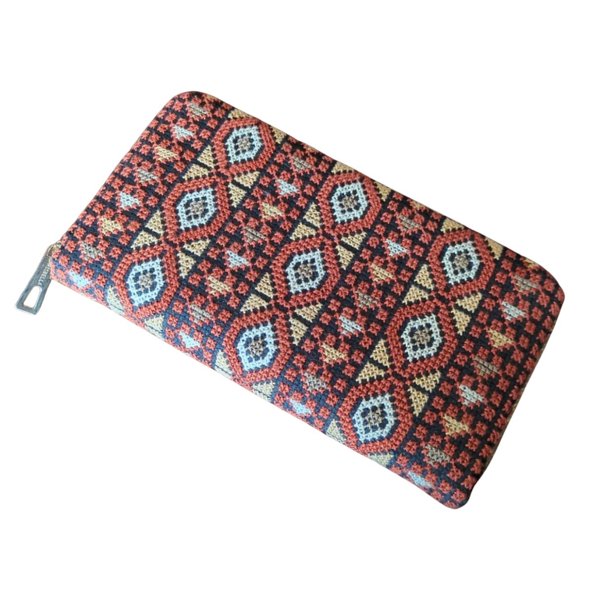 Carry a piece of Palestinian heritage with this bold, embroidered-inspired zip wallet—where tradition meets modern utility. A zip-up wallet featuring a vibrant, geometric Palestinian tatreez (embroidery) pattern in red, gold, black, and blue hues.