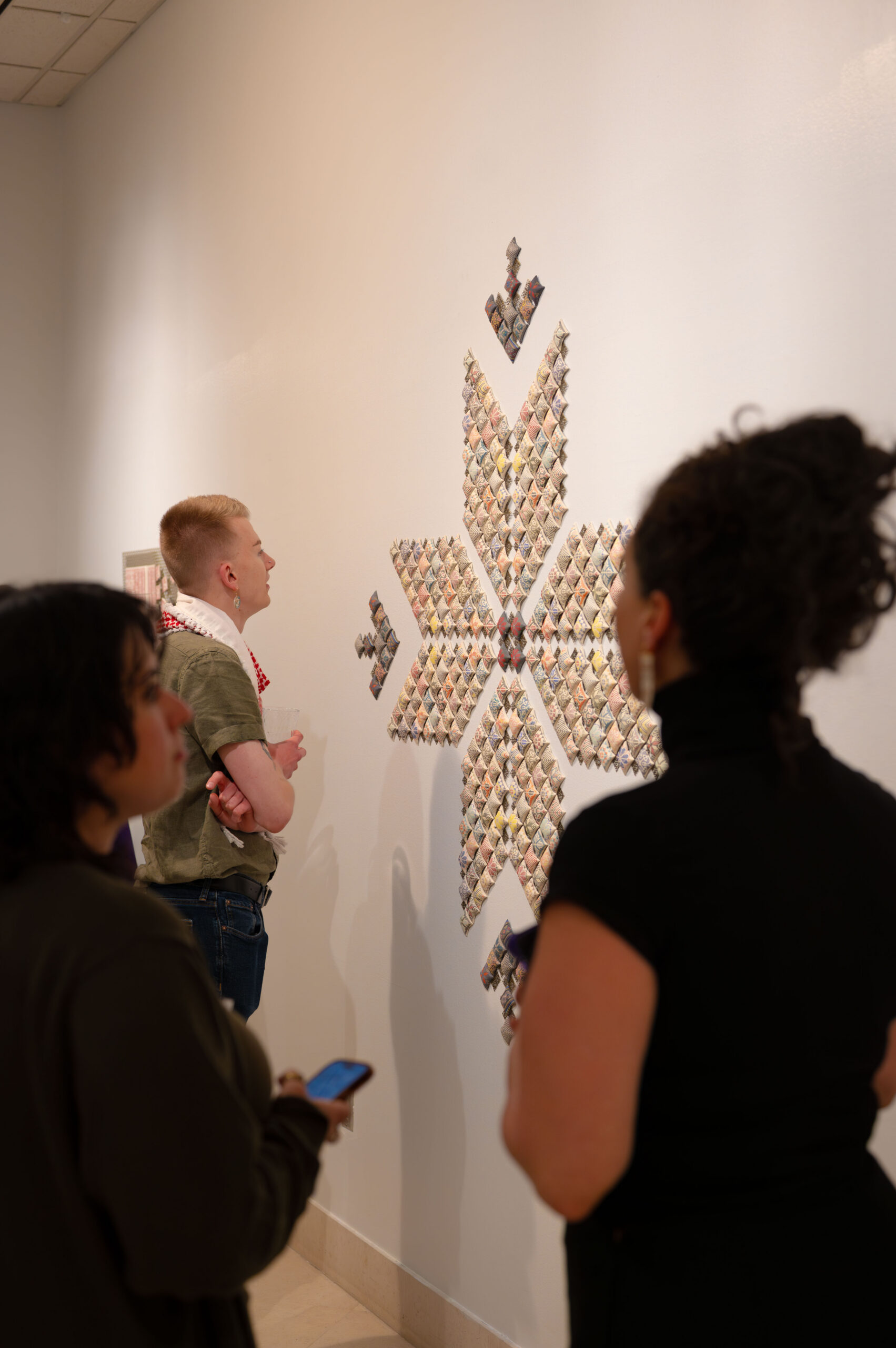Visitors viewing Palestinian ceramic wall installation inspired by tatreez patterns at museum exhibition
